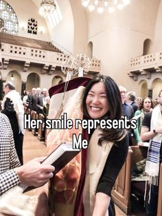 a woman smiling and holding a book in front of a man who is standing next to her