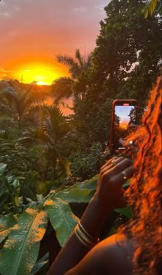 a woman taking a photo with her cell phone in the jungle at sunset or dawn