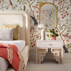 a bedroom with wallpaper and a pink dresser next to a bed in front of a mirror