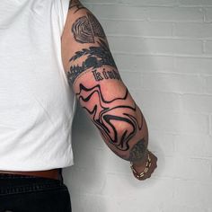 a man with a tattoo on his arm holding onto a wall and wearing a white t - shirt