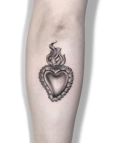 a black and white photo of a heart tattoo on the right leg with an ornate frame around it