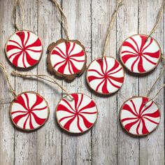 red and white peppermint ornaments hanging from string on wooden planked surface with wood background