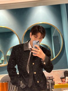 a man taking a selfie in front of a mirror while wearing a suit and tie