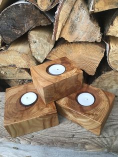 three wooden candles sitting on top of each other in front of wood stacked up and ready to be used