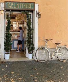 a man standing in front of a store with a bicycle parked outside the shop door