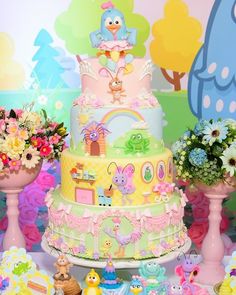 a multi layer cake sitting on top of a table next to flowers and vases