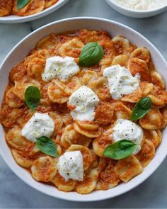 two bowls filled with pasta and cheese on top of a table