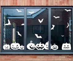 a window with halloween decorations on it and bats flying over the windows, behind which is a brick wall