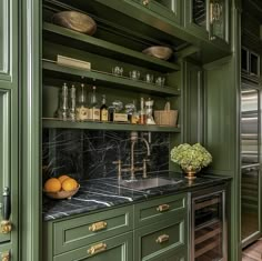 a kitchen with green cabinets and black marble counter tops, gold accents on the faucet