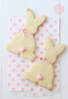 two cookies shaped like bunnies sitting on top of a polka dot tablecloth with pink bows