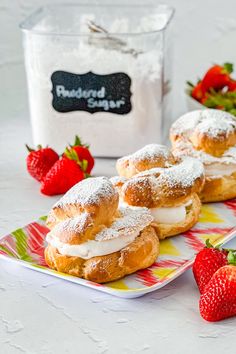 strawberry shortcakes with powdered sugar and fresh strawberries on the table next to them