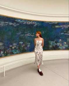 a woman standing in front of a large painting with water lillies on the wall