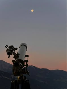 a telescope on top of a mountain with the moon in the sky behind it and mountains in the background