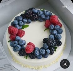 a white cake with berries and raspberries on top