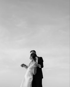 a man and woman standing next to each other on top of a beach near the ocean