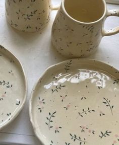 three plates and two mugs sitting on a window sill next to each other