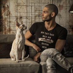 a man sitting on top of a couch next to a cat