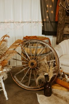 an old wagon wheel is surrounded by dried plants and other items in front of a white couch