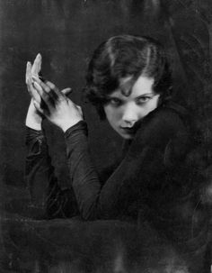 an old black and white photo of a woman holding her hands up to her face