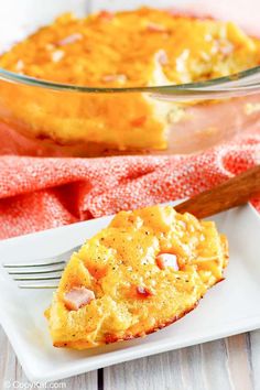 a slice of ham and cheese casserole on a white plate with a fork