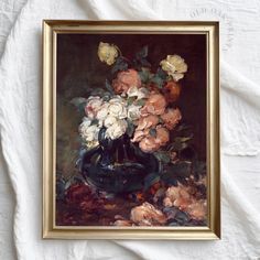 a painting of flowers in a black vase on a white cloth covered tablecloth with a gold frame