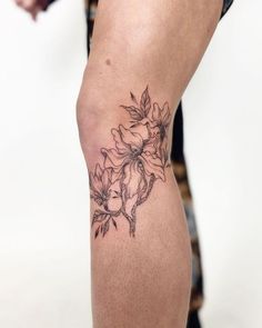 a woman's leg with a tattoo on it that has flowers and leaves on it