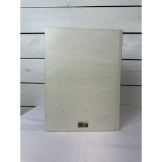 a white book sitting on top of a table next to a wooden wall behind it