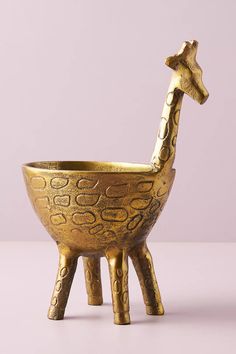 a golden giraffe shaped bowl sitting on top of a wooden table next to a purple wall