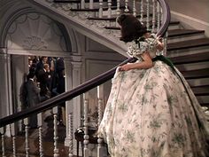 a woman in a white dress is walking down the stairs