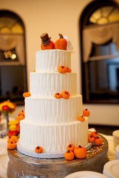 a three tiered white wedding cake with pumpkins on it