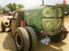 an old green tanker truck parked in the dirt