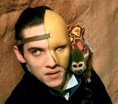 a man wearing a mask with a monkey on his shoulder and another animal behind him