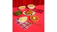 a table topped with lots of different types of food and desserts next to a red curtain