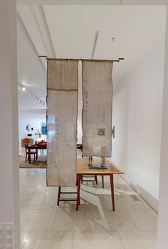 an open room with two pieces of cloth hanging from the ceiling and a table in front of it