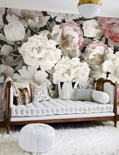 a white day bed sitting in front of a flower wallpapered wall with pink and white flowers on it