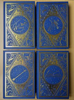 four blue and gold playing cards sitting on top of a wooden table