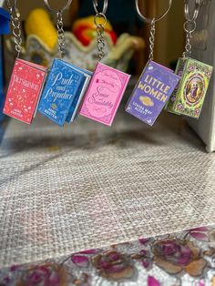 four little books are hanging from chains on a table