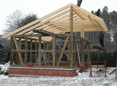 a house being built in the snow with some people working on it's roof