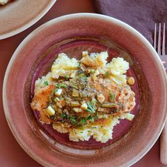 two plates with food on them sitting on a table next to silverware and utensils