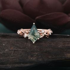 a green tourmaline ring sitting on top of a piece of wood