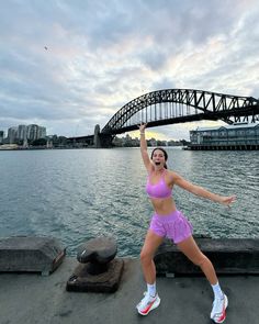 a woman standing on top of a pier holding a tennis racquet