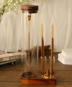 a glass vase with some sticks in it on a wooden table next to books and flowers