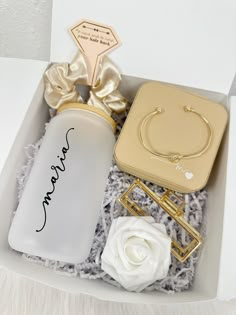 an open box with some jewelry and a white rose in it on a tablecloth