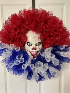 a creepy clown mask hanging on a door with red, white and blue tulle