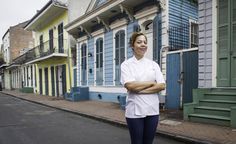 a woman is standing in front of some colorful buildings with her arms crossed and looking at the camera