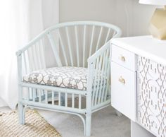 a white chair sitting next to a dresser with a lamp on it's side