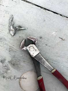 a pair of red handled pliers sitting on top of a piece of white wood