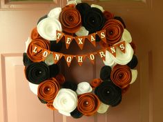 a wreath with texas longhorns on it hanging from the front door, decorated with orange and white flowers