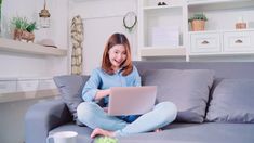 a woman sitting on a couch using a laptop computer