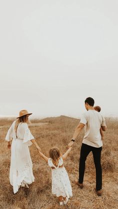 a family holding hands and walking through a field